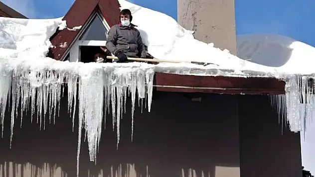 Çatılardaki dev buz sarkıtlarını saatlerce uğraşıp temizledi