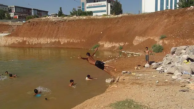 Çocuklar, inşaat temelini dolduran kirli suda yüzüyor