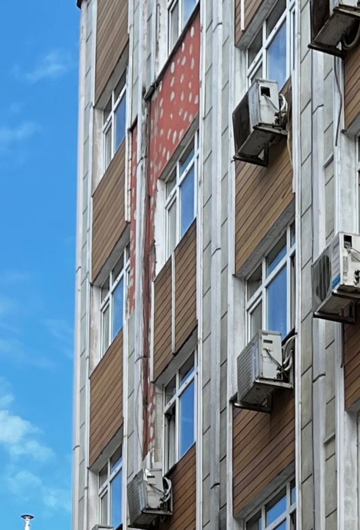 Kaldırımda yürürken, otelin dış cephe kaplaması üzerine düştü