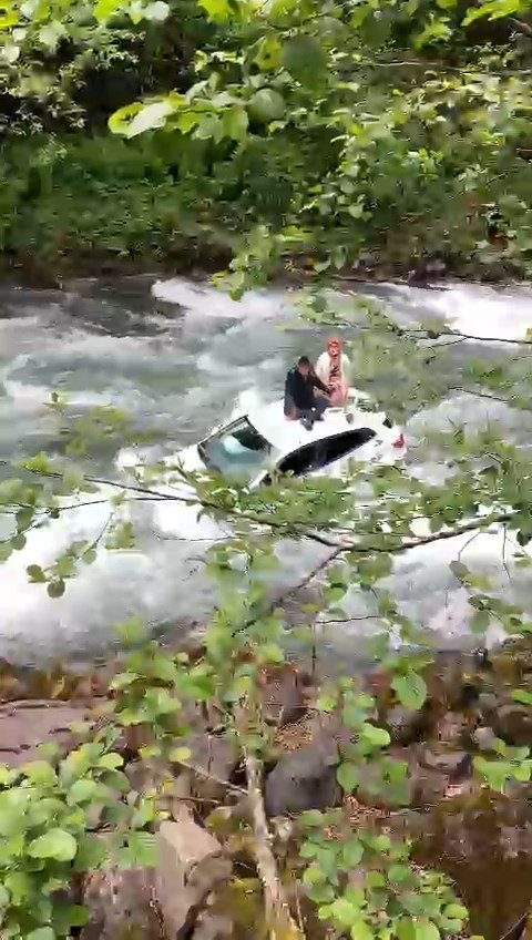 Dereye uçan otomobilin üzerine çıkıp kurtarılmayı beklediler