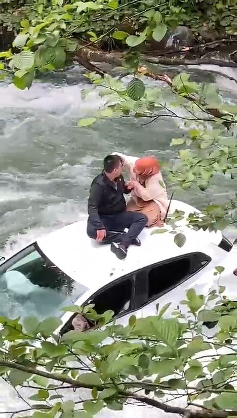 Dereye uçan otomobilin üzerine çıkıp kurtarılmayı beklediler