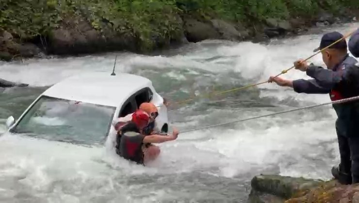 Dereye uçan otomobilin üzerine çıkıp kurtarılmayı beklediler