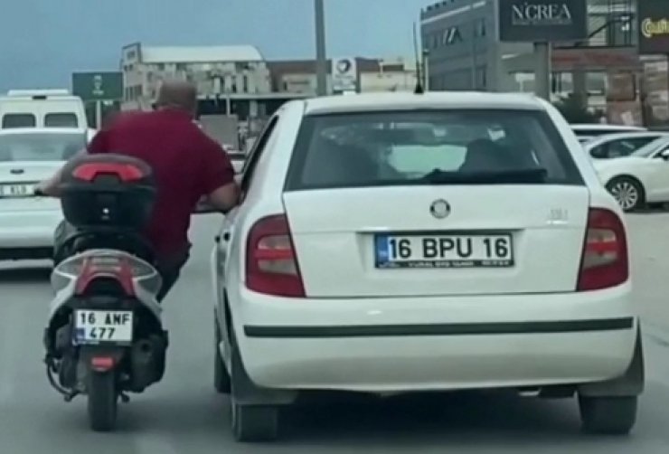 Otomobilin kapısına tutunarak sürücüyle sohbet etti