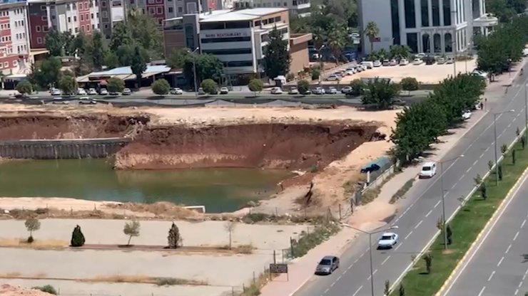 Çocuklar, inşaat temelini dolduran kirli suda yüzüyor